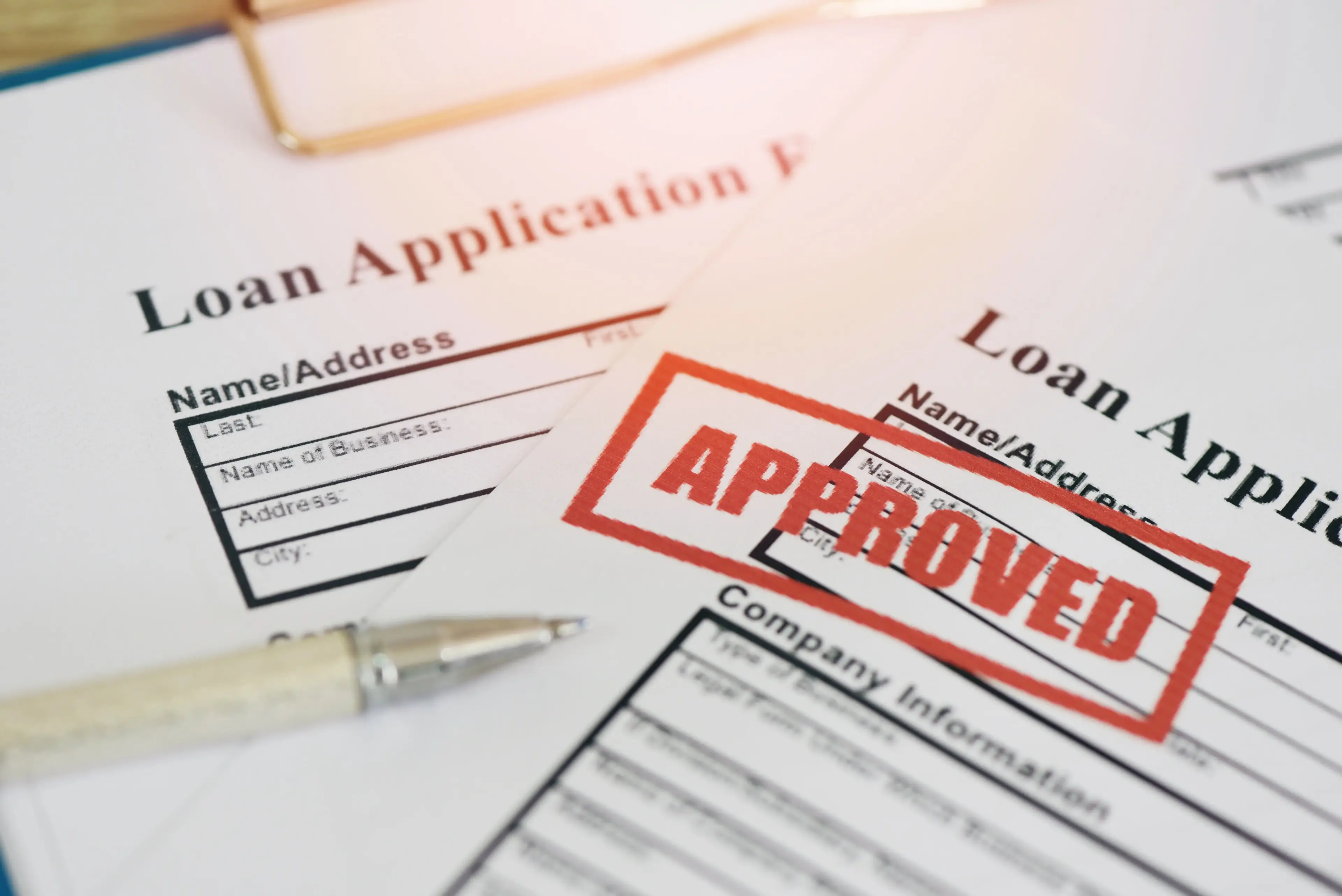 Loan applications scattered with one stamped "approved".