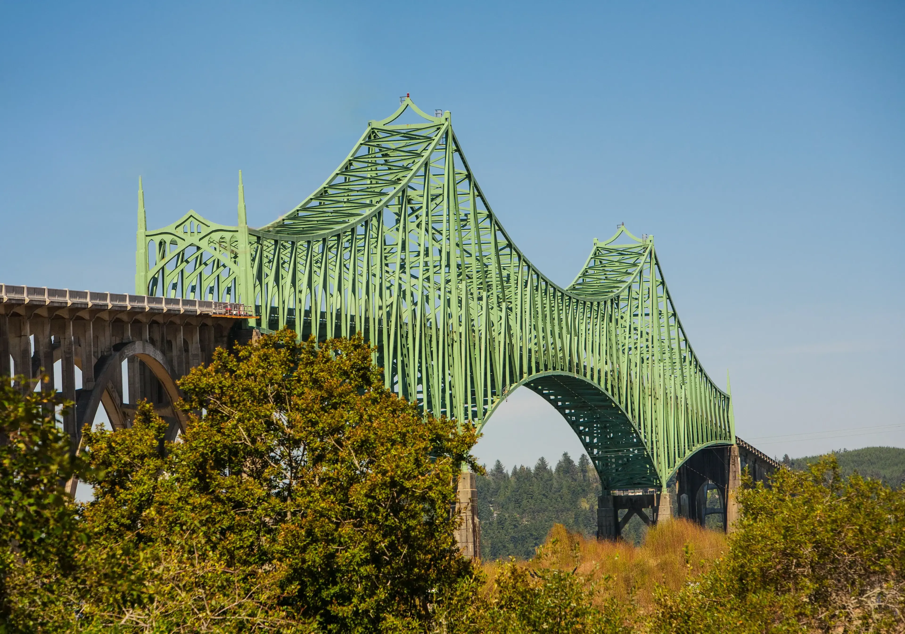 Green steel bridge structure against a clear blue sky, symbolizing bridge financing solutions.