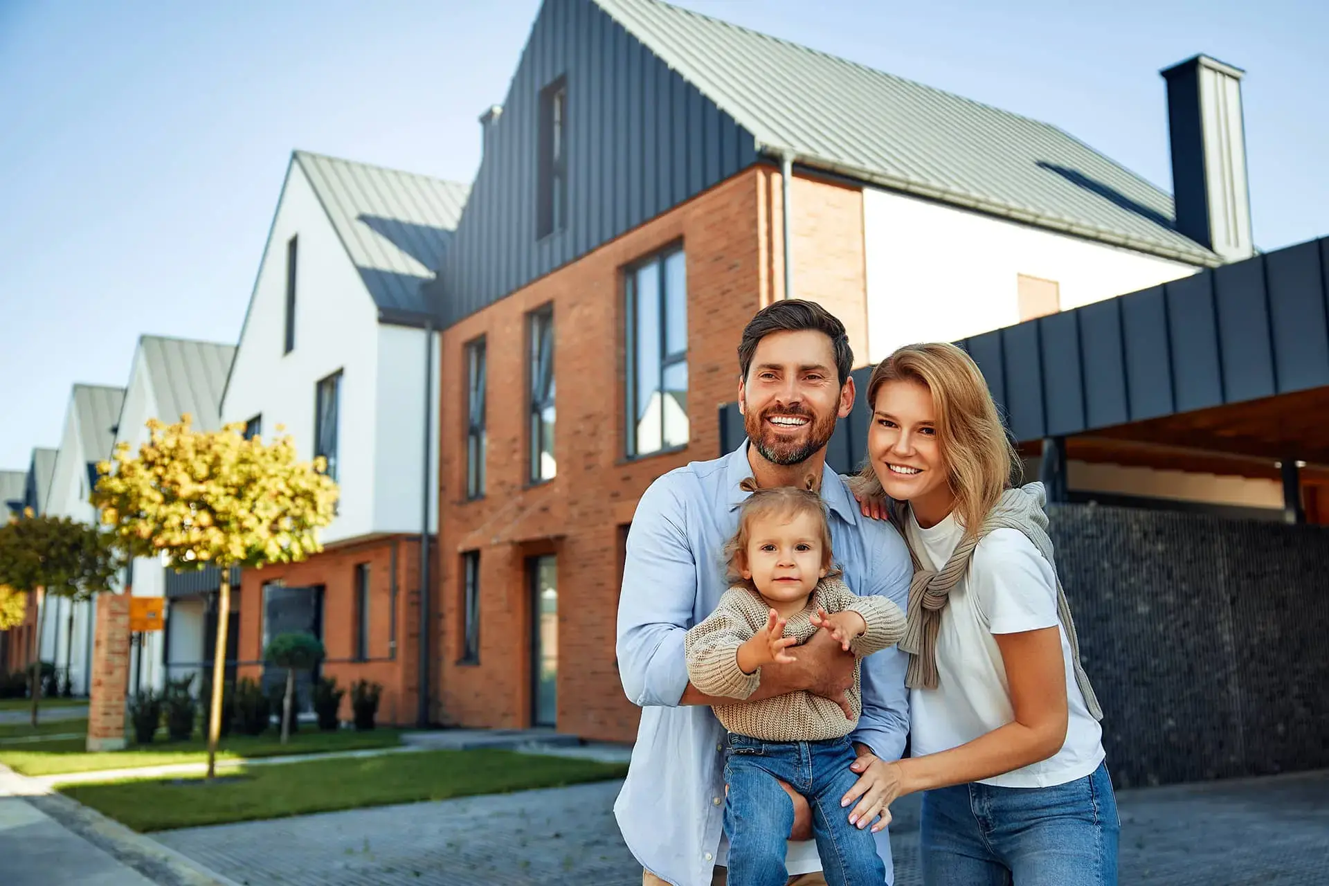 Family standing in front of house taking a picture.