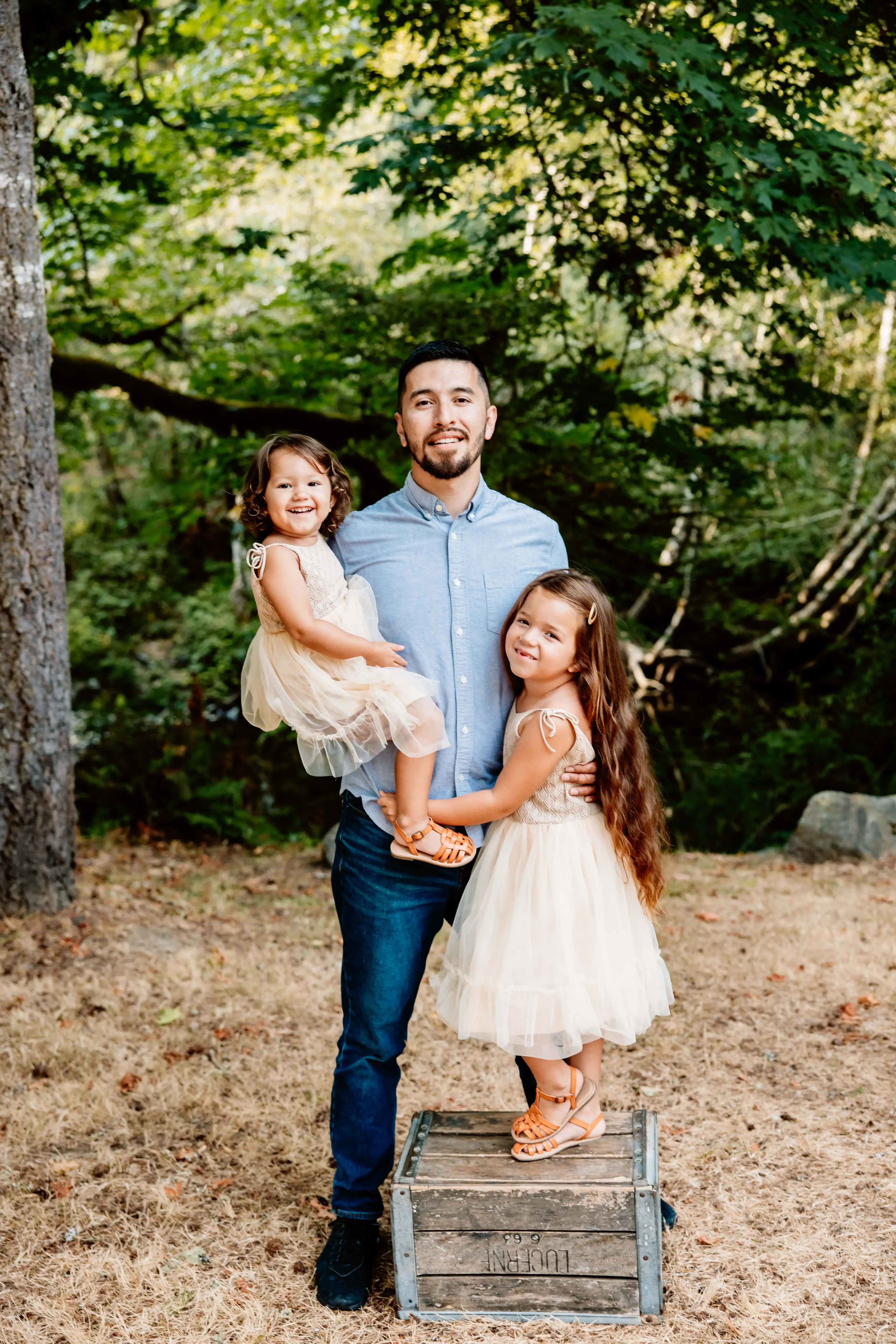 Freddy holding his daughters for a picture with the woods as a background.